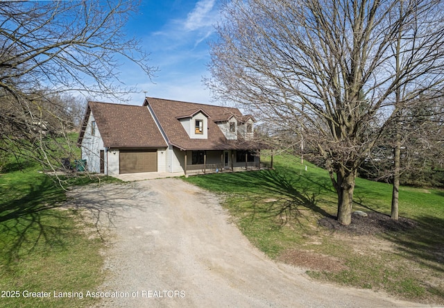view of front of house featuring covered porch, an attached garage, dirt driveway, and a front lawn