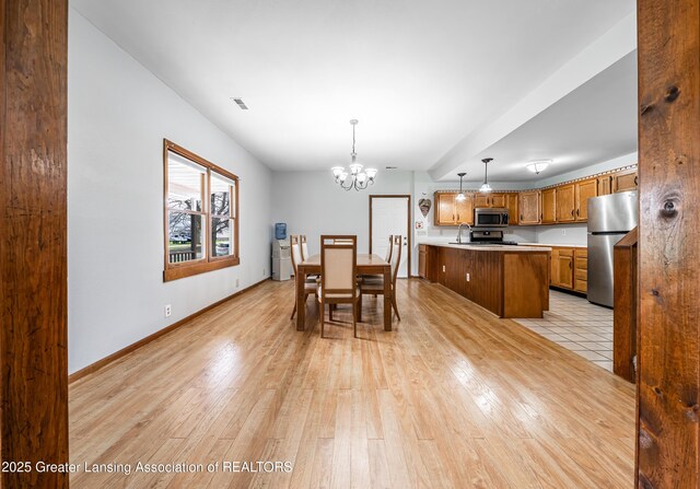 dining room with baseboards, light wood-type flooring, and an inviting chandelier
