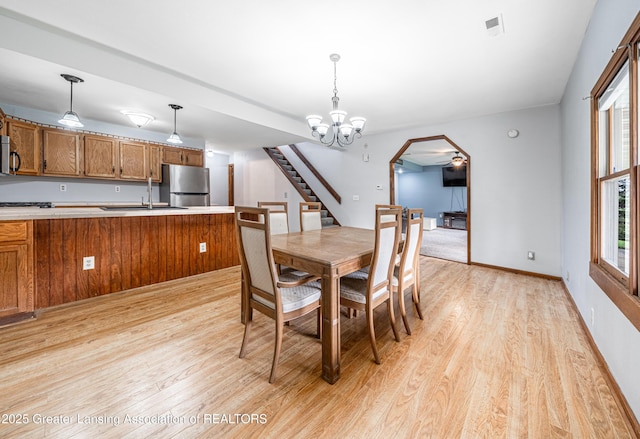 dining space with visible vents, light wood-type flooring, arched walkways, and stairway