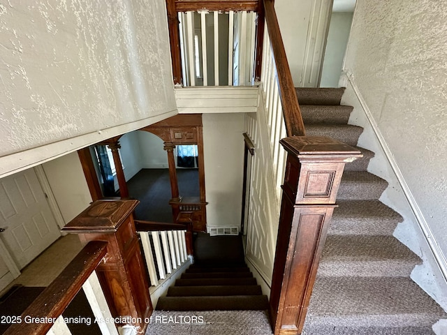 staircase featuring carpet floors and a textured wall