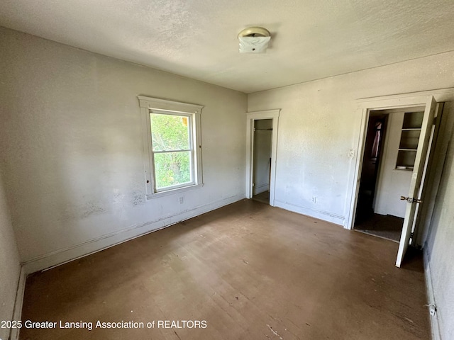 unfurnished bedroom with baseboards, concrete flooring, and a textured ceiling