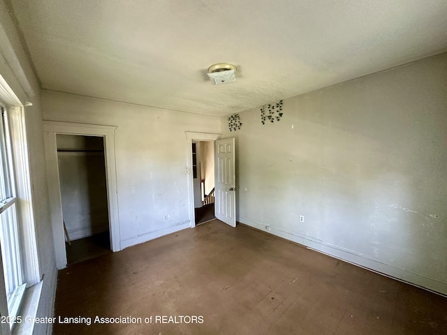 unfurnished bedroom featuring baseboards, concrete floors, and a closet