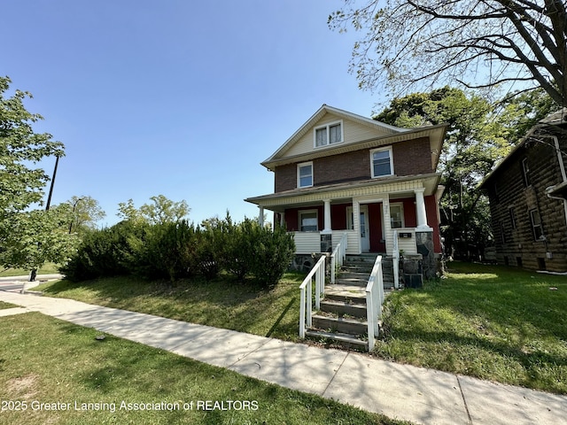 american foursquare style home featuring brick siding, a front lawn, and covered porch
