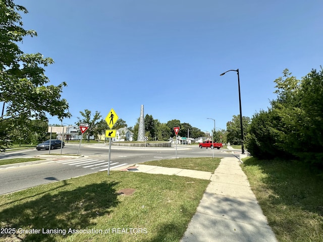 view of street with curbs, traffic signs, street lights, and sidewalks