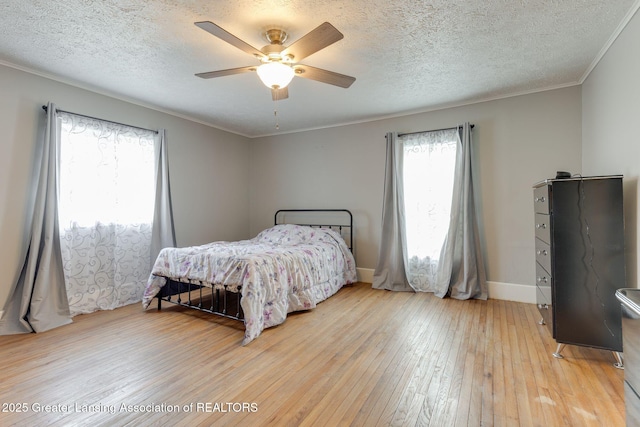 bedroom with ornamental molding, baseboards, light wood-type flooring, a textured ceiling, and a ceiling fan