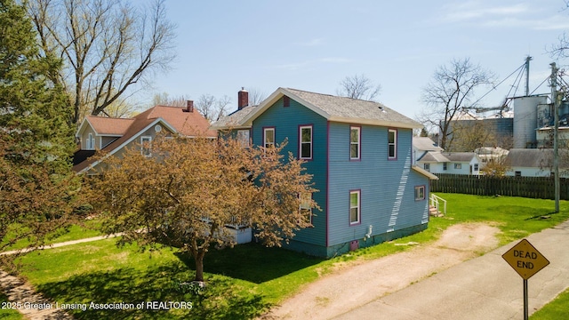 view of home's exterior with driveway, fence, a yard, and a chimney