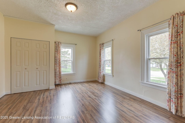unfurnished bedroom with a closet, baseboards, a textured ceiling, and wood finished floors