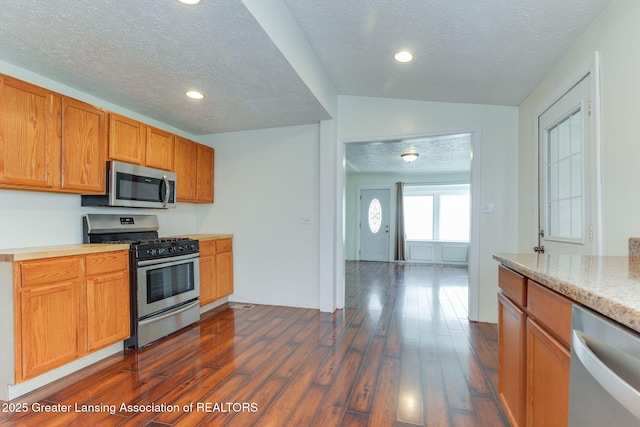 kitchen with appliances with stainless steel finishes, light countertops, a textured ceiling, recessed lighting, and dark wood-style floors