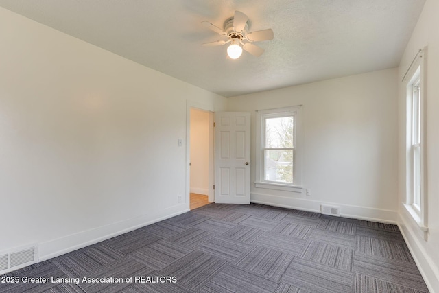 empty room featuring baseboards, dark colored carpet, and visible vents