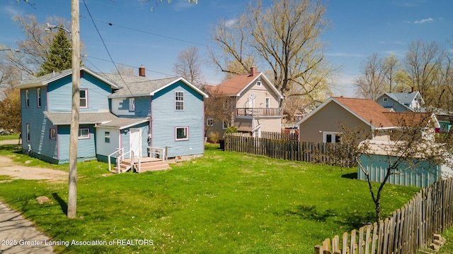 rear view of property with fence and a yard