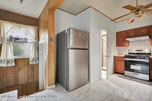 1600 S Pennsylvania Ave, Lansing, MI 48910 - kitchen featuring stainless steel appliances, under cabinet range hood, light marble finish flooring, ceiling fan, and tasteful backsplash