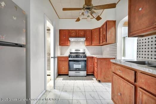 1600 S Pennsylvania Ave, Lansing, MI 48910 - kitchen with appliances with stainless steel finishes, exhaust hood, ceiling fan, and backsplash