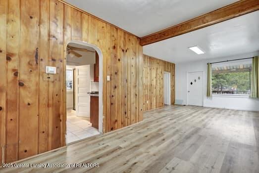 1600 S Pennsylvania Ave, Lansing, MI 48910 - unfurnished room with wooden walls, arched walkways, light wood finished floors, and beam ceiling
