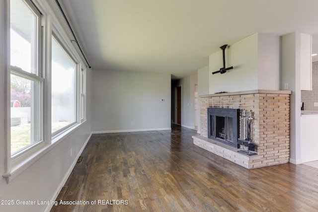 unfurnished living room with baseboards, wood finished floors, and a fireplace