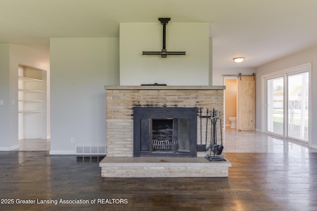 details featuring visible vents, a fireplace, built in shelves, wood finished floors, and baseboards