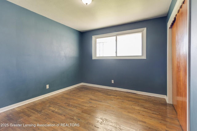unfurnished bedroom featuring a closet, baseboards, and wood finished floors