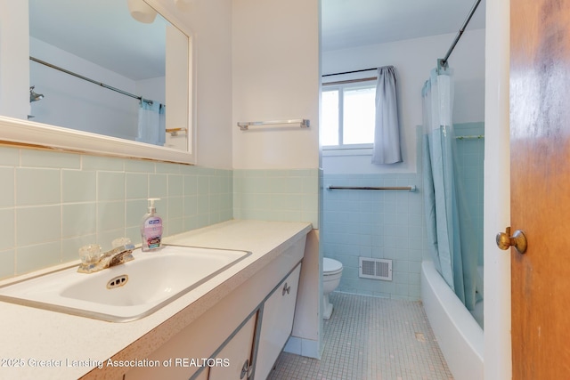 bathroom with visible vents, toilet, tile walls, a wainscoted wall, and tile patterned floors