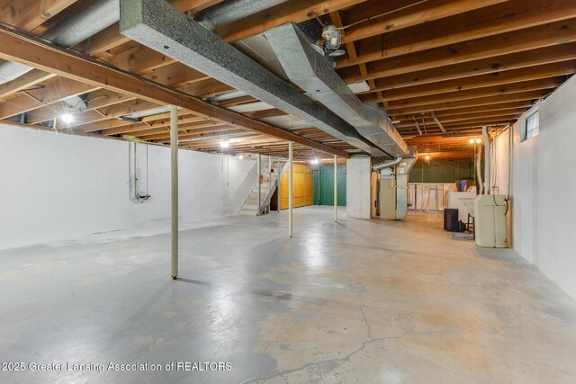 unfinished basement with heating unit and stairway