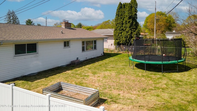 view of yard with central air condition unit, a trampoline, fence, and a vegetable garden
