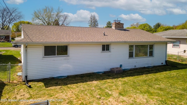 rear view of house with a lawn, central AC unit, fence, and a chimney
