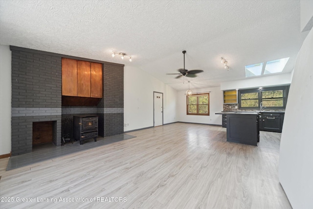 1971 N Michigan Rd, Eaton Rapids, MI 48827 - unfurnished living room with baseboards, lofted ceiling with skylight, ceiling fan, a textured ceiling, and light wood-style flooring