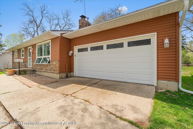 view of front facade with concrete driveway, a chimney, and a garage