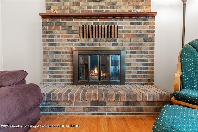 interior details featuring a brick fireplace and wood finished floors