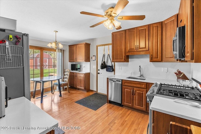 kitchen with light countertops, brown cabinets, a sink, light wood finished floors, and stainless steel appliances