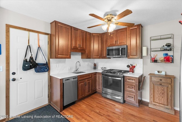 kitchen with ceiling fan, a sink, light wood-style floors, light countertops, and stainless steel appliances