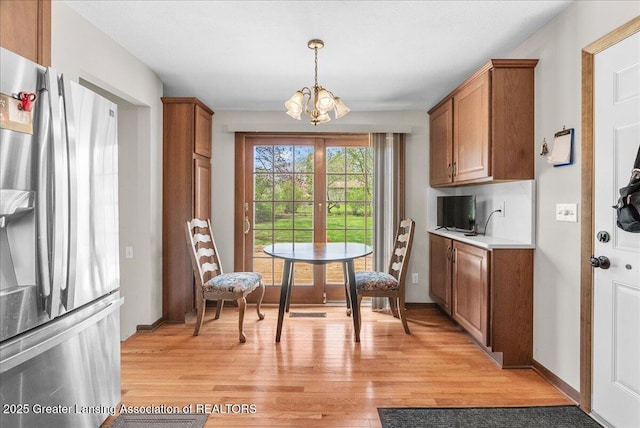 dining room with light wood-type flooring, baseboards, and a notable chandelier