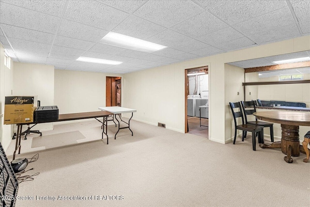 carpeted office featuring washing machine and dryer, baseboards, visible vents, and a drop ceiling