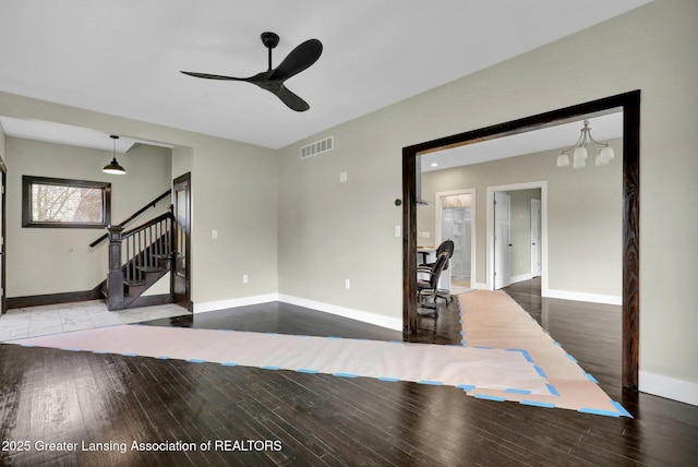 1127 W Saginaw St, Lansing, MI 48915 - unfurnished living room with visible vents, wood finished floors, baseboards, stairway, and a ceiling fan