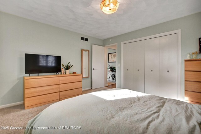 carpeted bedroom with a closet, baseboards, and visible vents