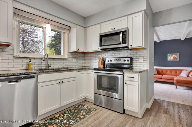 kitchen featuring white cabinets, appliances with stainless steel finishes, a sink, and light wood-type flooring