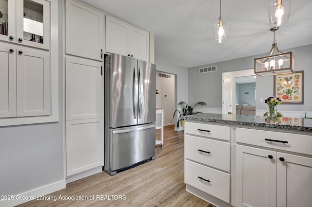 kitchen featuring baseboards, freestanding refrigerator, light wood finished floors, and visible vents