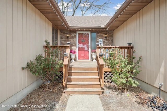 view of exterior entry featuring a deck and roof with shingles