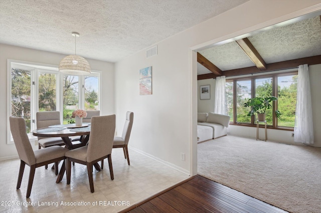 dining room with beamed ceiling, baseboards, visible vents, and plenty of natural light