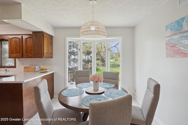 dining space with a textured ceiling, baseboards, visible vents, and a wealth of natural light