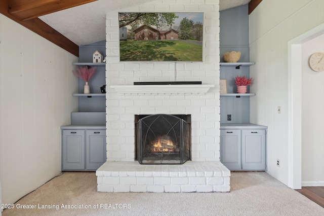 unfurnished living room with carpet floors, vaulted ceiling with beams, and a brick fireplace