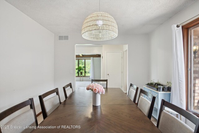 unfurnished dining area with visible vents, a textured ceiling, and a chandelier