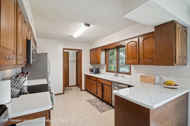 kitchen featuring light floors, light countertops, brown cabinets, a sink, and appliances with stainless steel finishes
