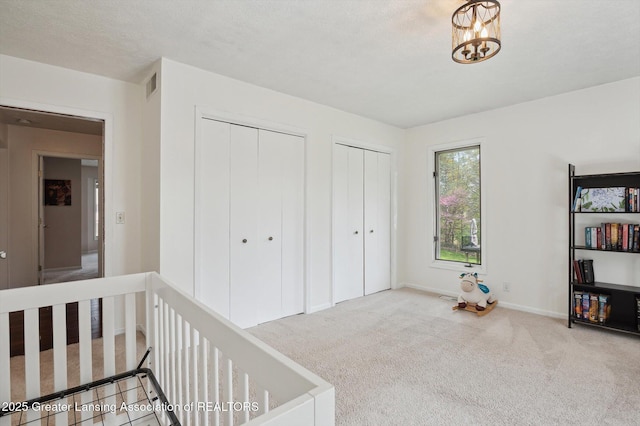 interior space featuring a chandelier, baseboards, multiple closets, and visible vents