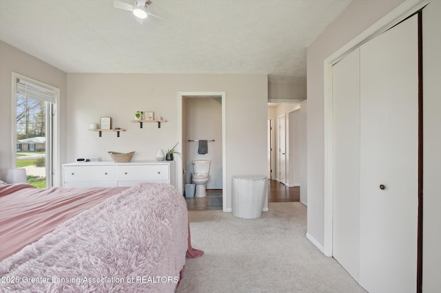 bedroom featuring connected bathroom, baseboards, light carpet, and a closet