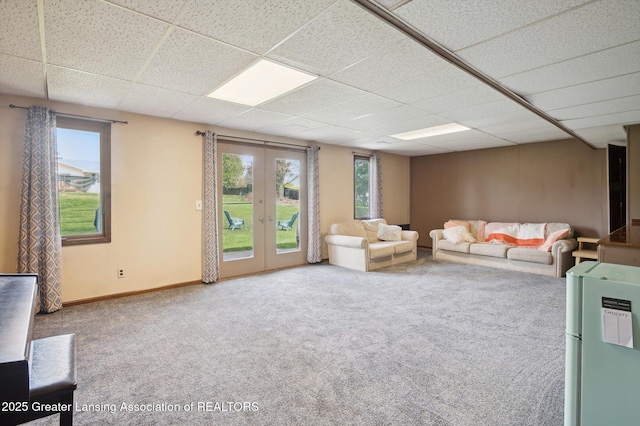 unfurnished living room with carpet floors, french doors, plenty of natural light, and a paneled ceiling