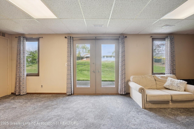 carpeted living area featuring visible vents, a drop ceiling, and french doors