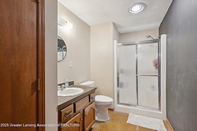 bathroom with vanity, a shower stall, toilet, and a textured ceiling