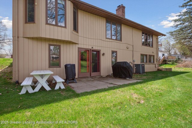 back of property with a lawn, a chimney, central AC, and a patio area