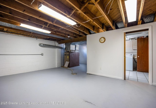 below grade area featuring concrete block wall and washer and clothes dryer