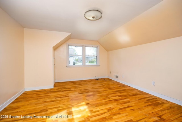 bonus room with light wood-style floors, baseboards, visible vents, and vaulted ceiling