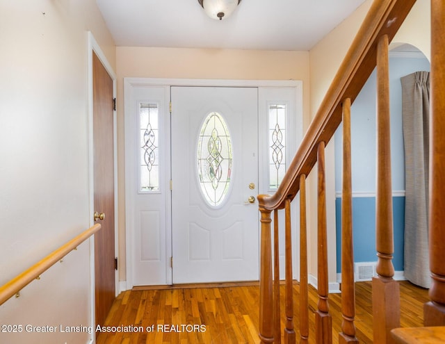 foyer entrance with visible vents, stairs, wood finished floors, and a wealth of natural light